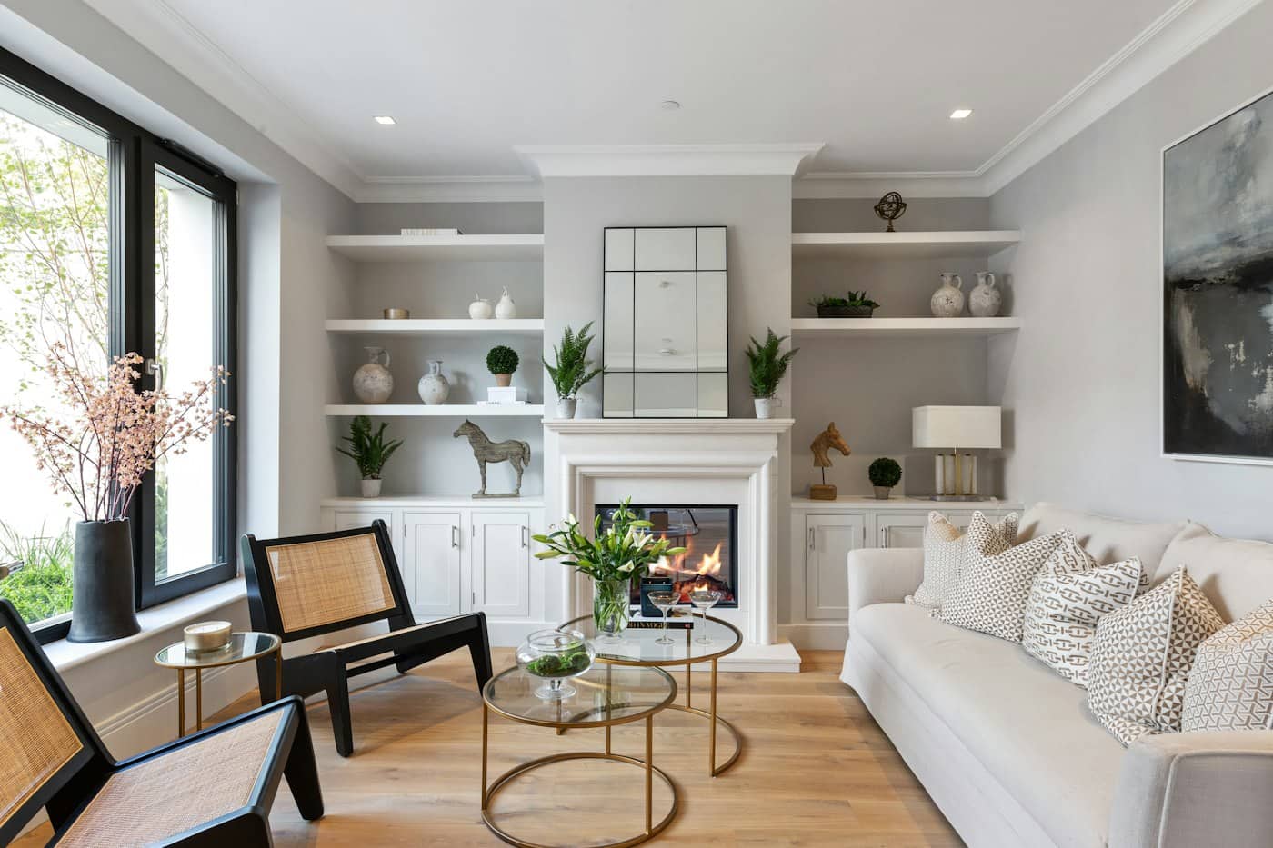 Living room with recessed downlights, alcove shelving either side of a chimney breast and a lit fireplace.