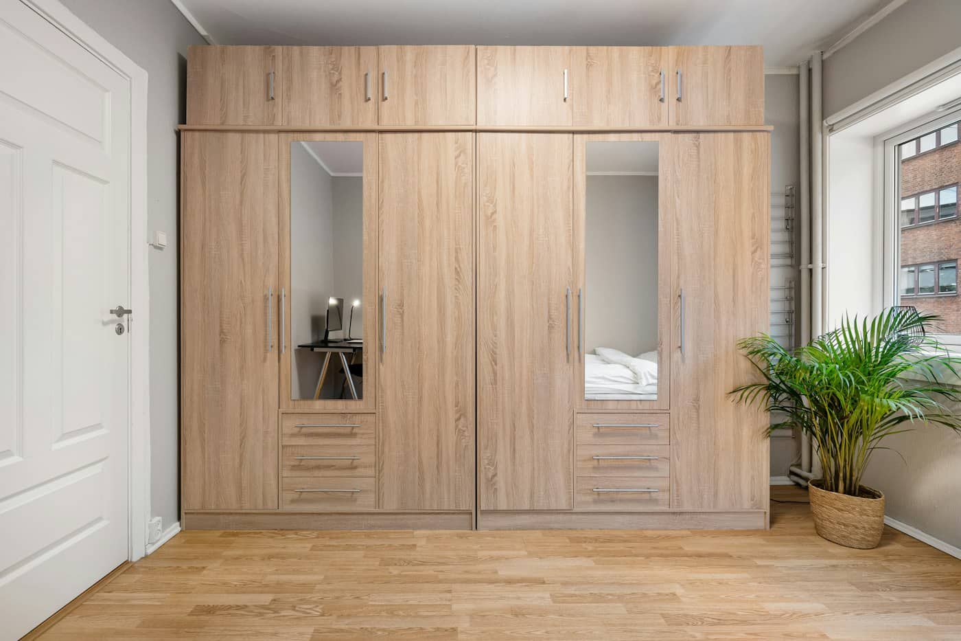 Assembled oak-effect wardrobe with mirrored doors filling a bedroom wall