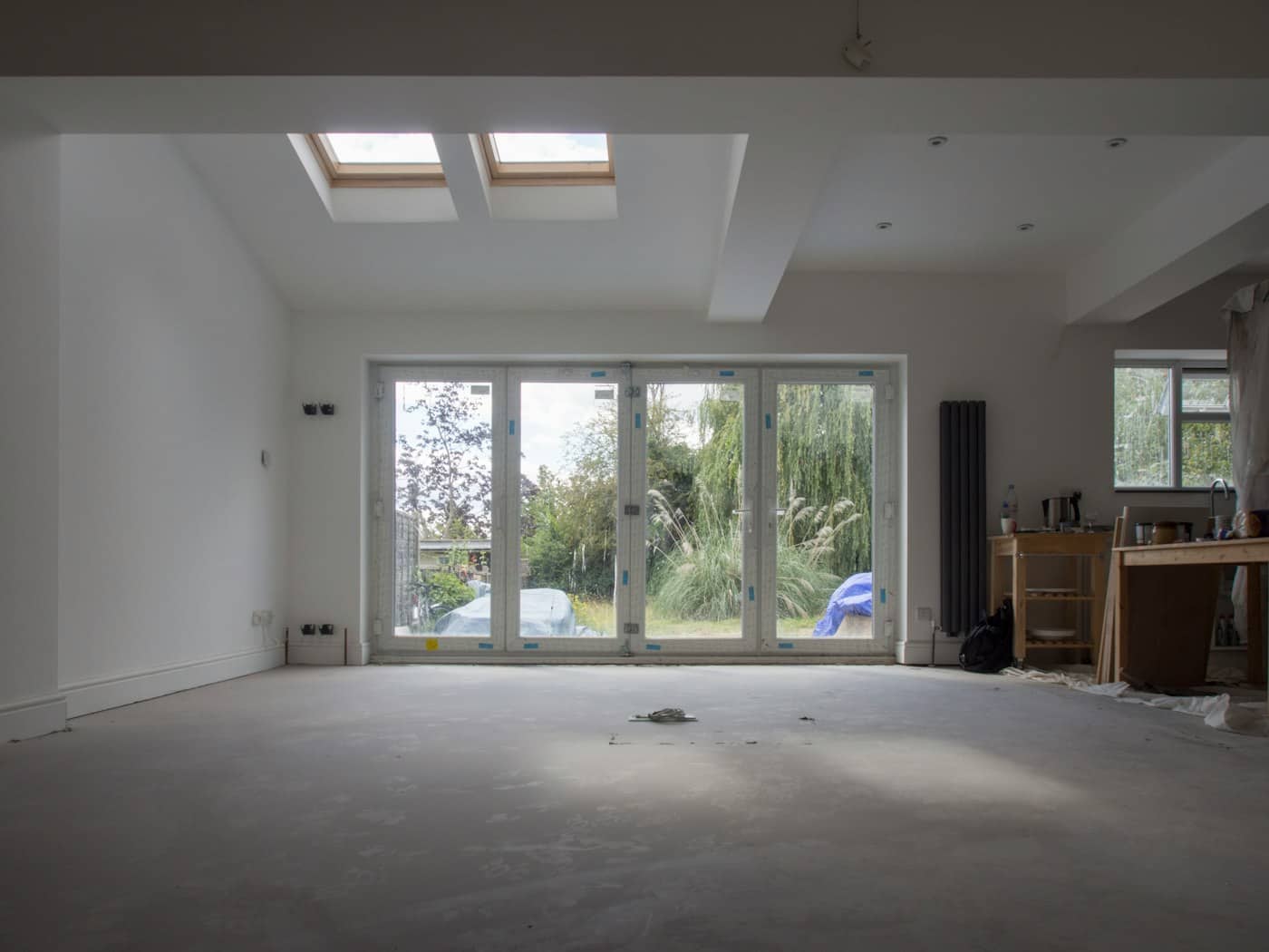 Freshly finished single-storey rear extension with white walls, roof lights and glazed doors onto a garden