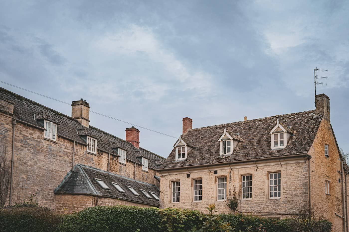 Stone houses with stone-tiled roofs, dormers and chimney stacks under a cloudy sky